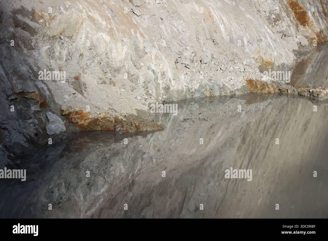 Unterirdische Höhle mit klarem Salzwasser, das raue graue Mineralsteinmauern reflektiert, die kalte Atmosphäre in tiefer Höhlenlandschaft zeigen Stockfoto