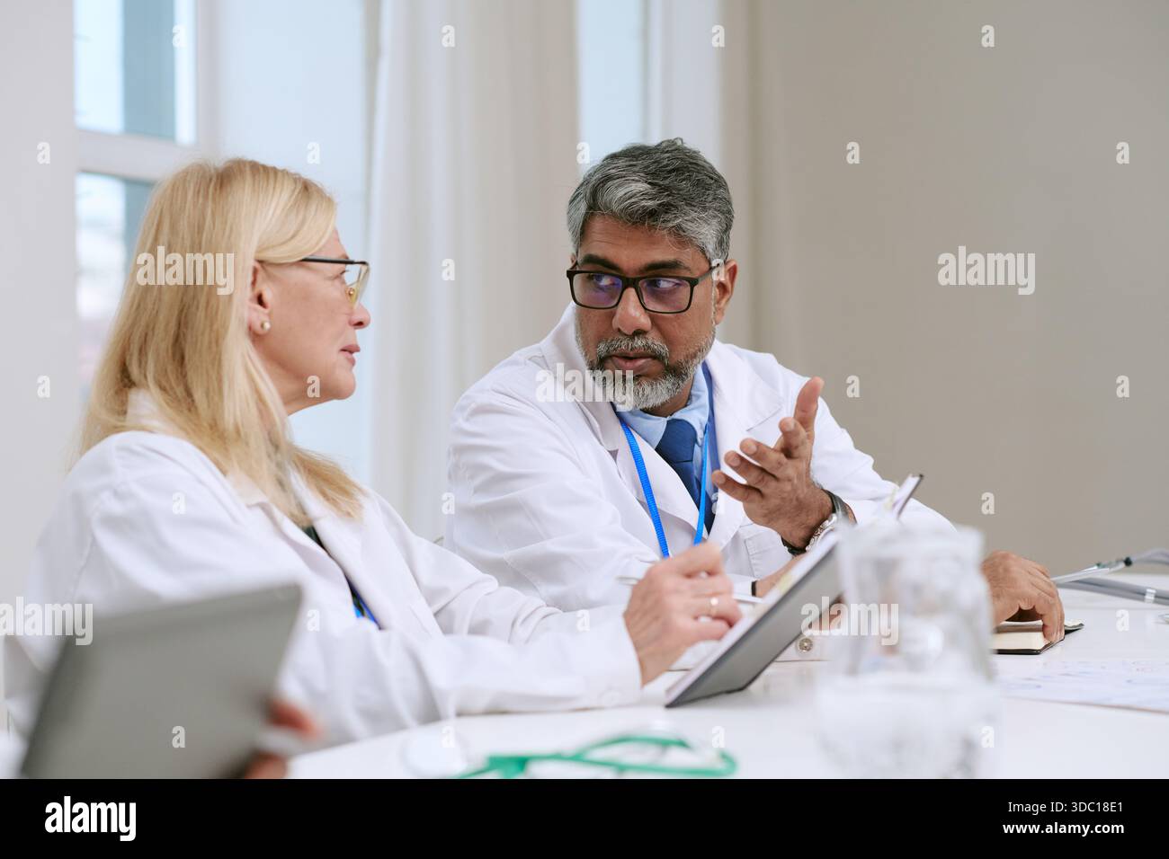 Frau mittleren Alters und südasiatischer Mann mittleren Alters diskutieren medizinischen Bericht Stockfoto