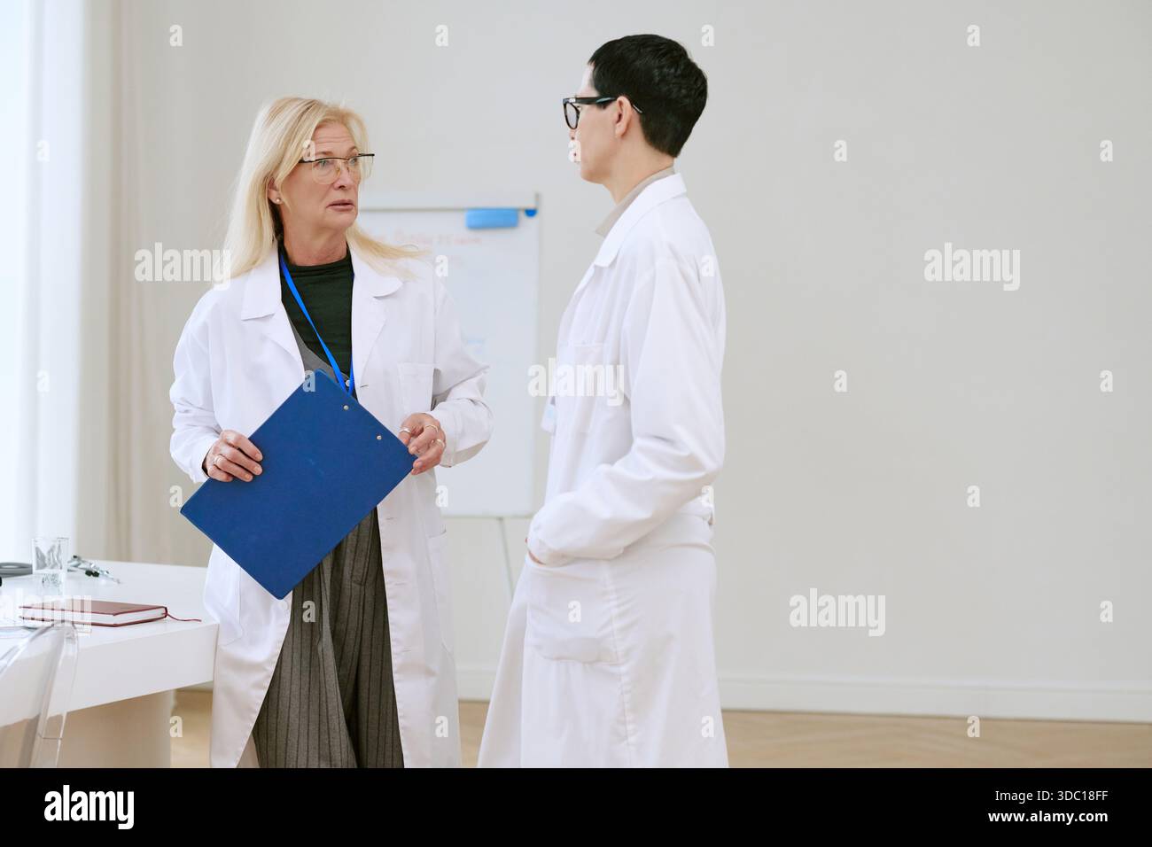 Zwei Frauen Mittleren Alters, Die Drinnen Über Medizinischen Fall Diskutieren Stockfoto