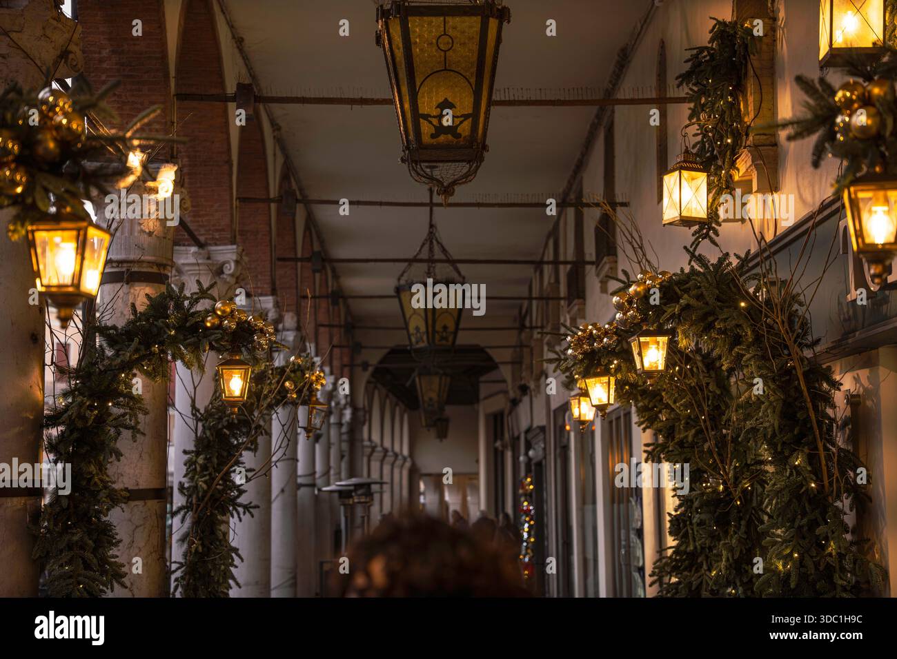 Rovigo, italien 18. dezember 2025: Beleuchtete Laternen und grüne Girlanden schmücken einen alten Bogengang und schaffen eine festliche, elegante und friedliche Ho Stockfoto