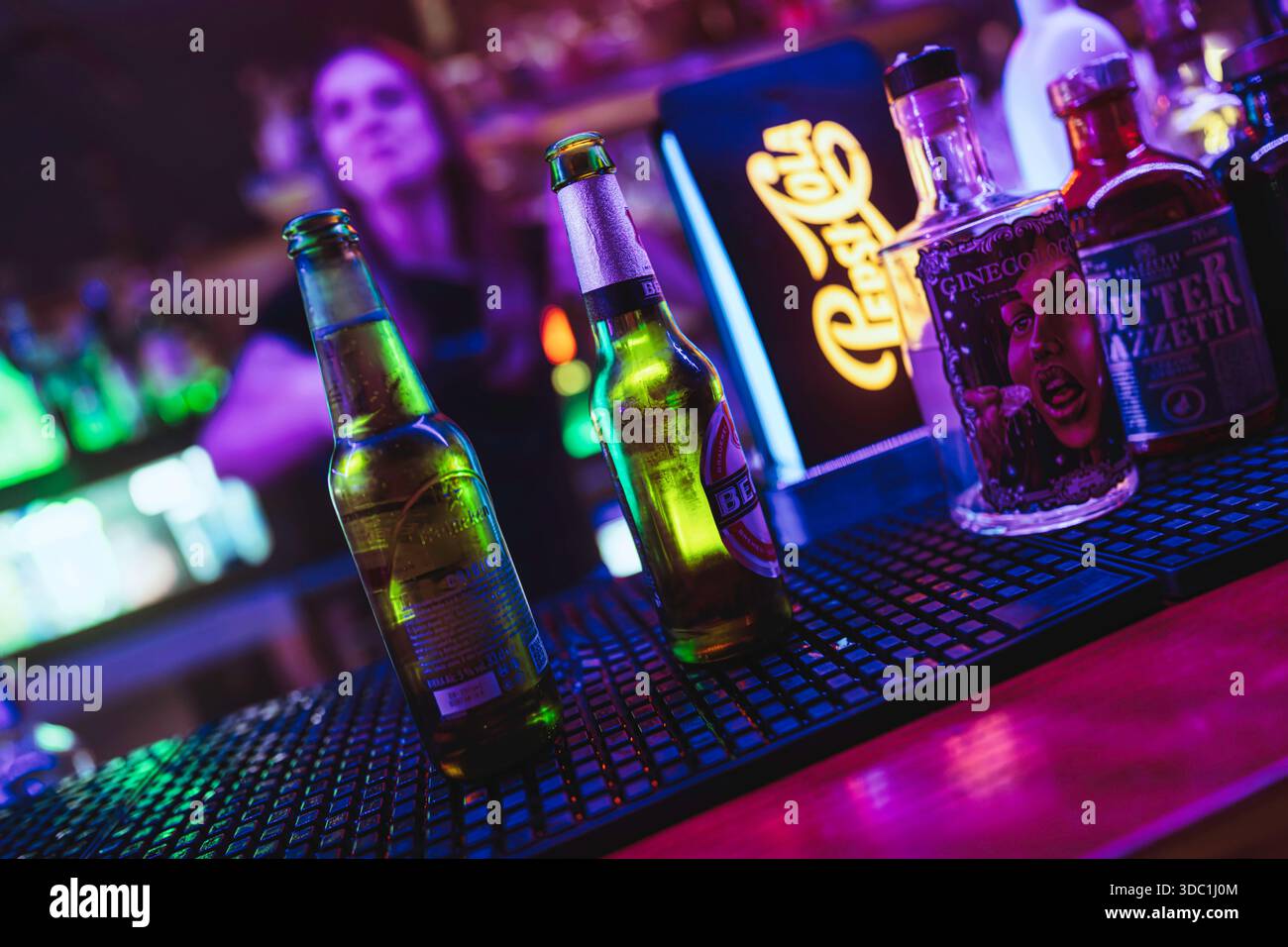 Rovigo, italien 18. dezember 2025: Bar mit erfrischenden Bierflaschen und Spirituosen unter leuchtenden Neonlichtern, bereit für Nachtleben und Unterhaltung Stockfoto
