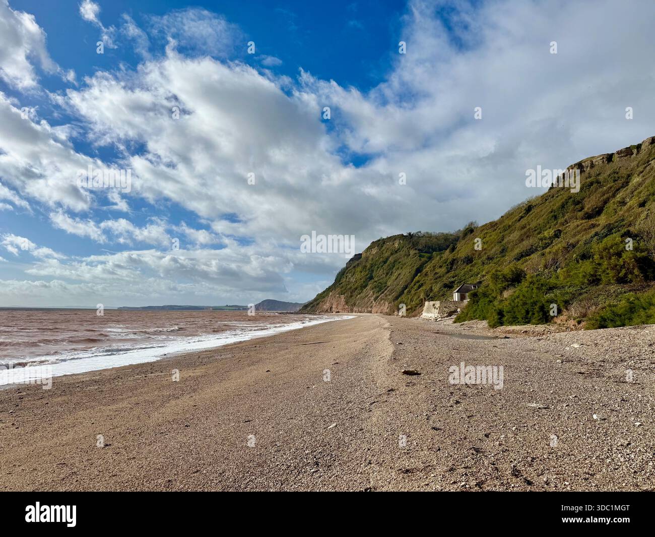 Kieselstrand in Weston Mouth, East Devon, mit Küstenklippen und Wellen entlang der Jurassic Coast. - Smartphone-aufgenommenes Stockfoto