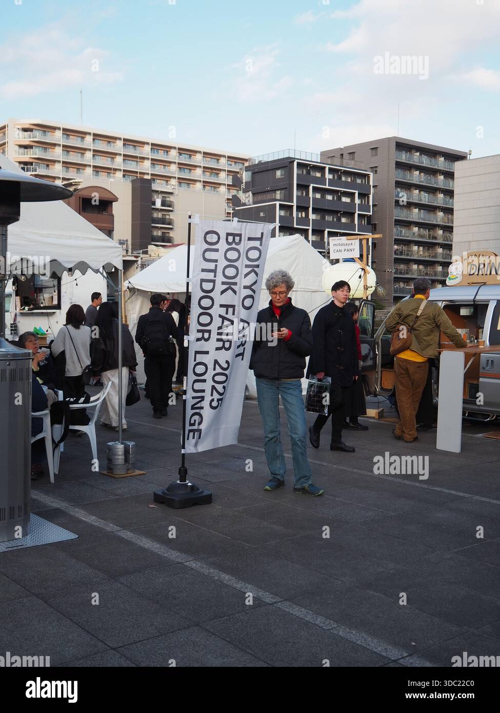 Besucher der Tokyo Art Book Fair 2025 Outdoor Lounge mit Bannern und Ständen Stockfoto