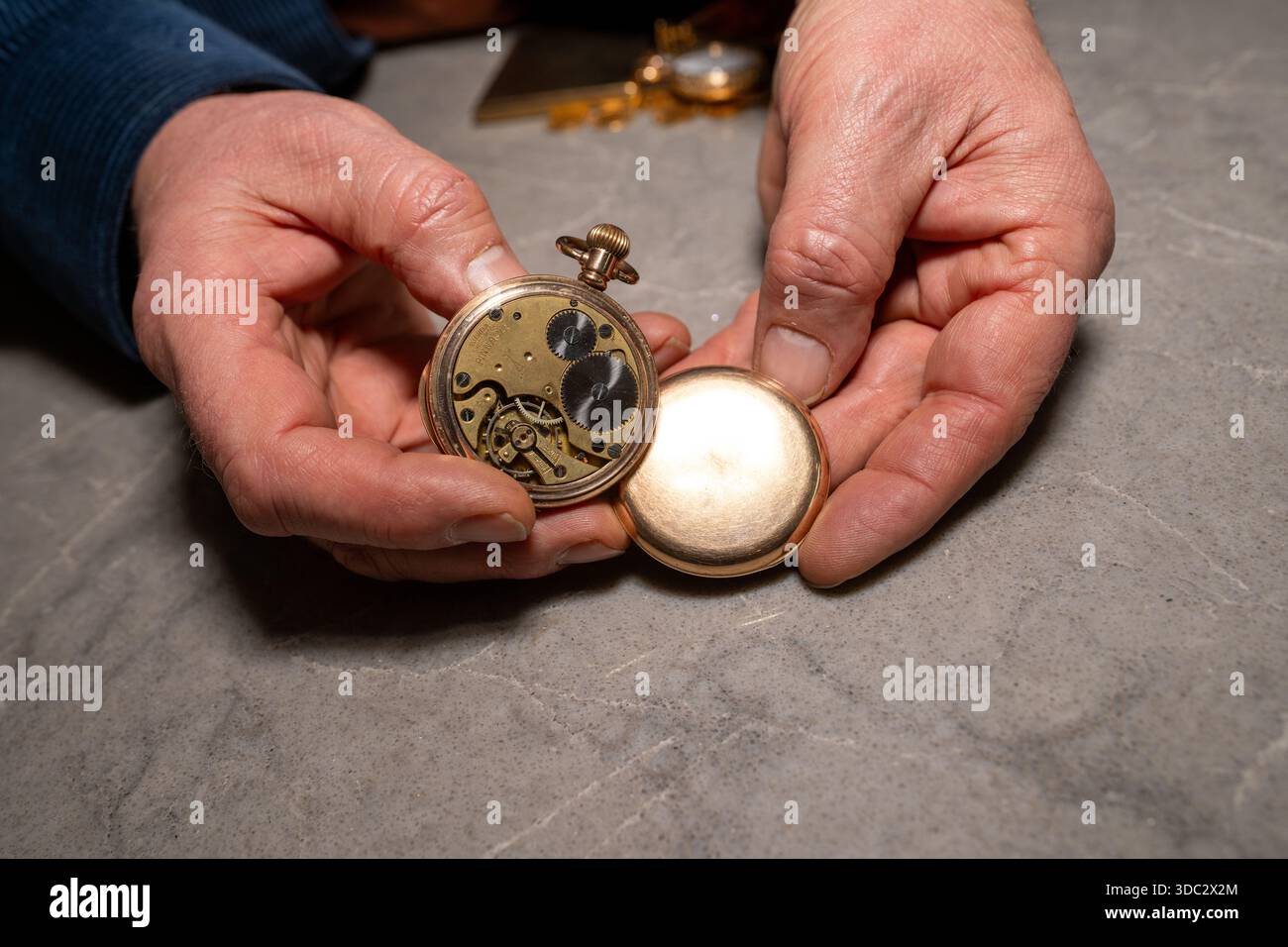 Die Hand des Mannes hält alte goldene Uhr offen und zeigt einen Mechanismus Stockfoto