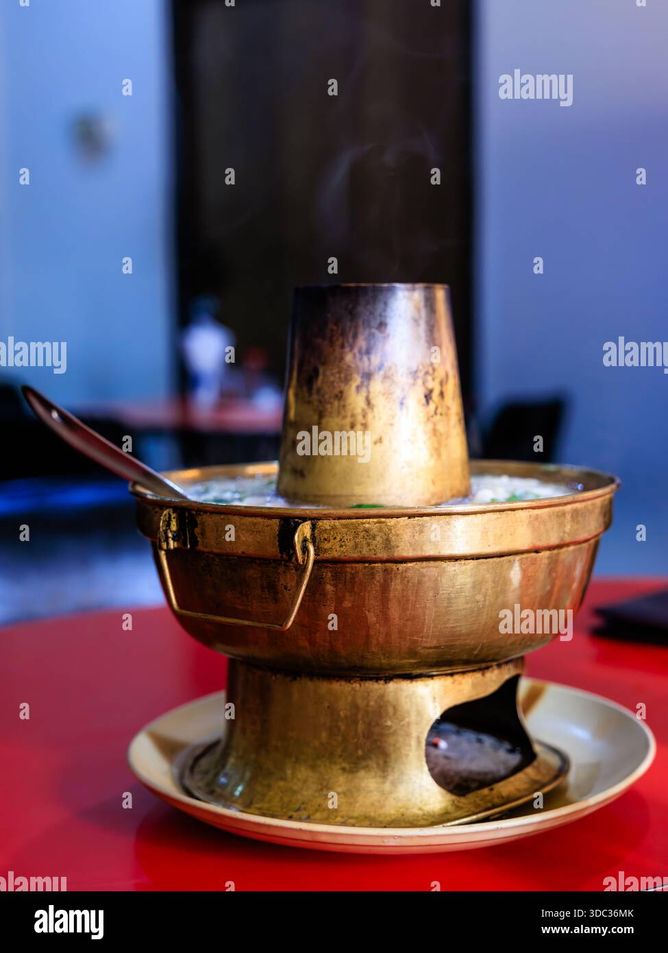 Ein rustikaler Messingtopf mit einem Brenner und einem Schornstein ist voll von kochender chinesischer Kaminsuppe im Eau Chew Restaurant kalkutta Stockfoto
