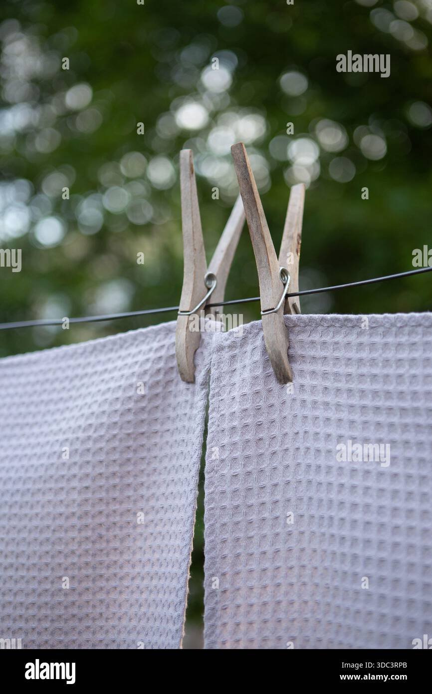 Farbenfrohe Textilhandtücher hängen draußen an einer Wäscheleine. Frisch gewaschener Stoff trocknet bei natürlichem Sonnenlicht mit Wäscheständer, weicher Textur, Sommer-atm Stockfoto