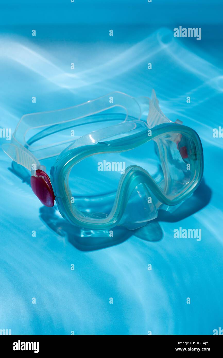 Flache Aufnahme einer blauen Tauchermaske über türkisblauem Hintergrund. Minimalistisches Foto der Tauchmaske unter Wasser Stockfoto