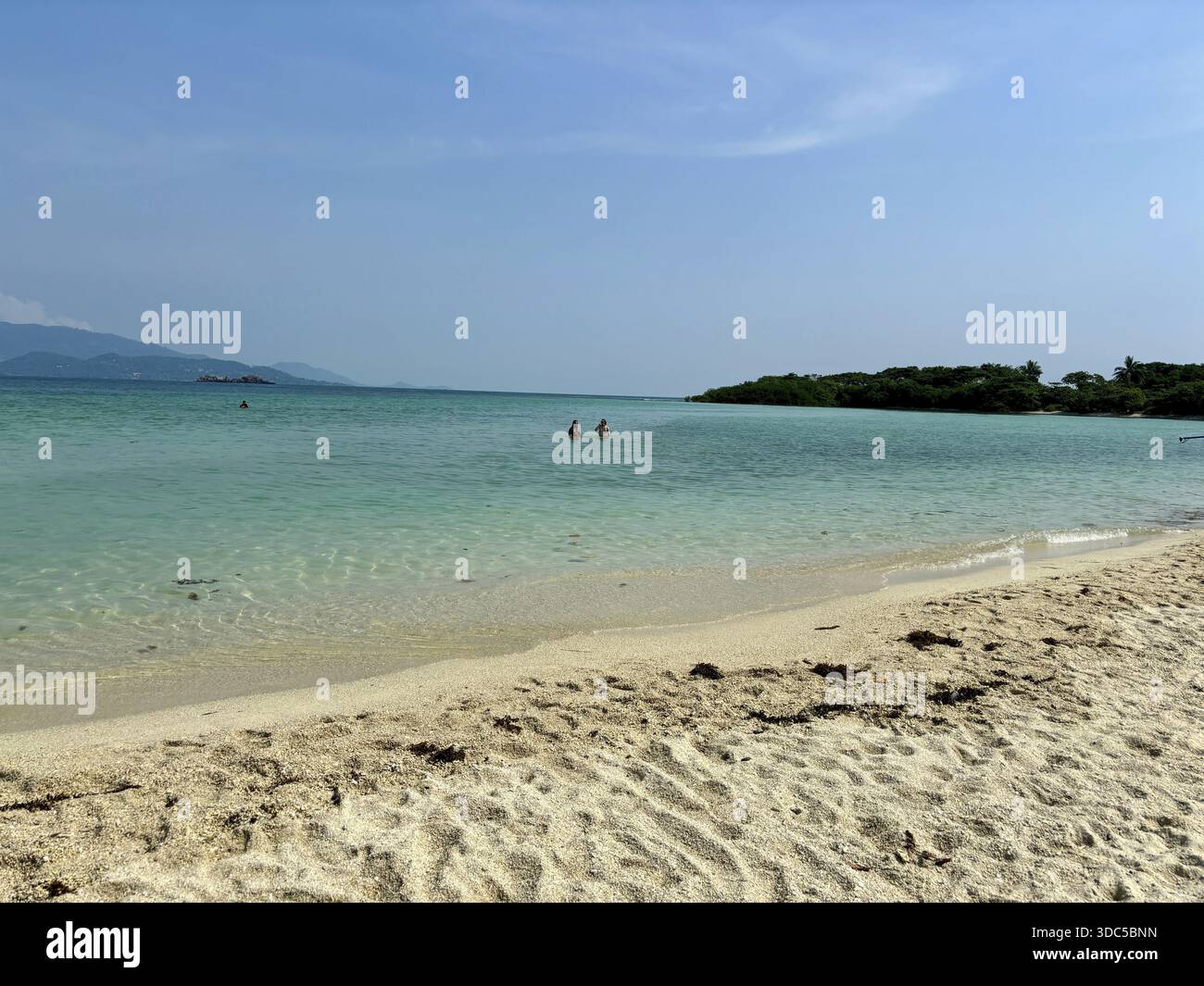 Klarer Himmel über einem ruhigen Strand mit türkisfarbenem Wasser und Badegästen, Thailand Stockfoto