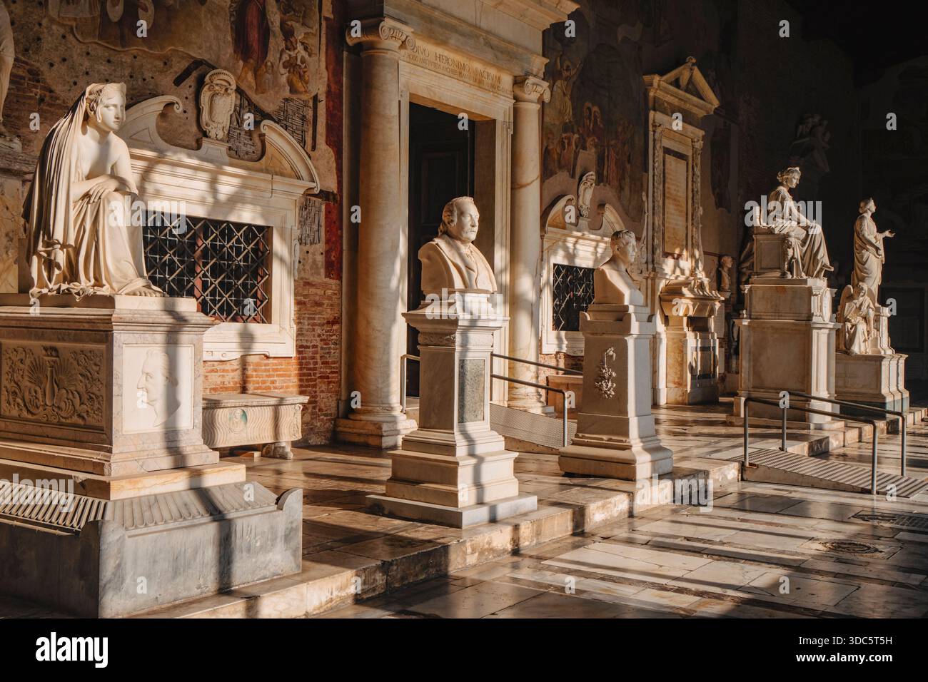 Pisa, Italien - 26. Juni 2025: Grabdenkmäler aus Marmor säumen die Ostgalerie des Camposanto Monumentale, beleuchtet durch Sonnenlicht, das die Lichter von Stockfoto