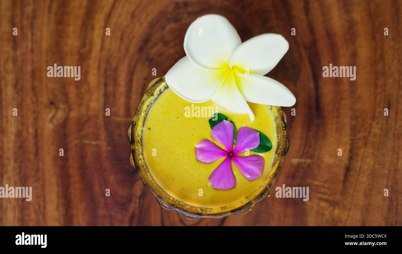 Ubtan oder natürliches Körperpeeling für glänzende Haut in einer Schüssel auf hölzernem Hintergrund. Traditionelle ayurvedische Gesichtspackung mit haldi, Milch, Rosenwasser Stockfoto