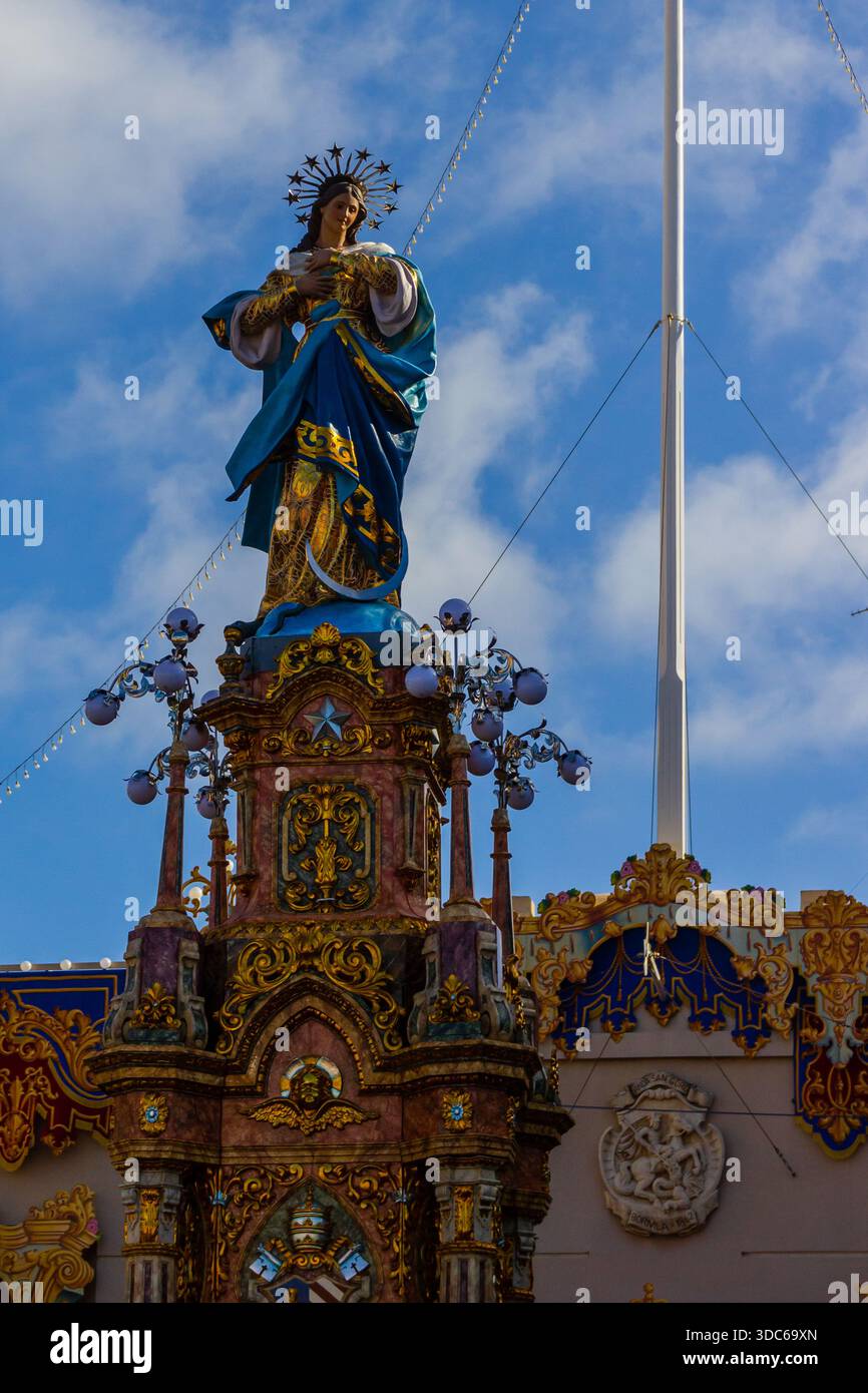 Verzierte Virgin Mary Statue Auf Dem Farbenfrohen Schrein Inmitten Festlicher Outdoor-Einrichtung Mit Blauen Bademänteln Stockfoto