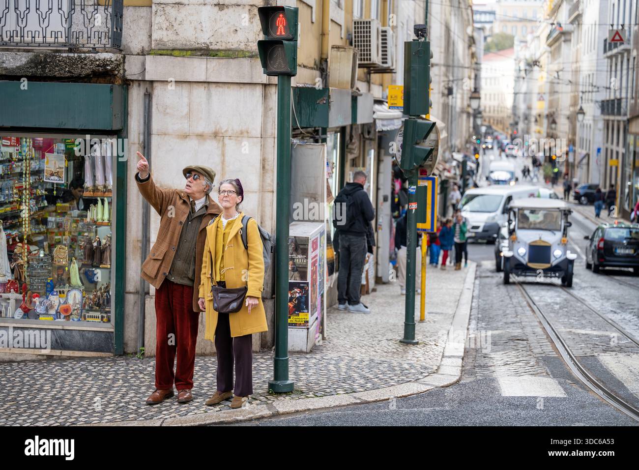 Lissabon Portugal 5. Dezember 2025. Fußgänger Autos und ein kleines Taxi teilen sich eine enge Straße mit Straßenbahnschienen in Lissabon. Stockfoto