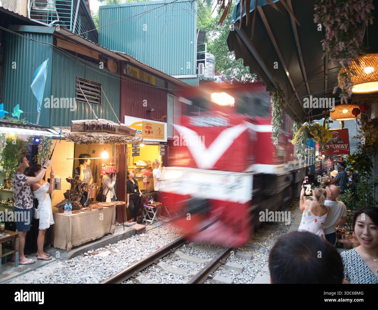 hanoi-Vietnam-10. August 2019, Touristen drängen die Gleise, während ein rasanter Zug durch Hanois enge Bahnstraße (phố Đường Tàu) fährt. Ein berühmter und c Stockfoto