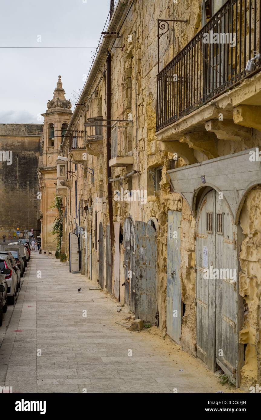 Eine ruhige Straße in Mdina, Malta, zeigt die historische Architektur der Stadt. Die verwitterten Kalksteinbauten mit ihren alten Türen und Balkonen, Ev Stockfoto