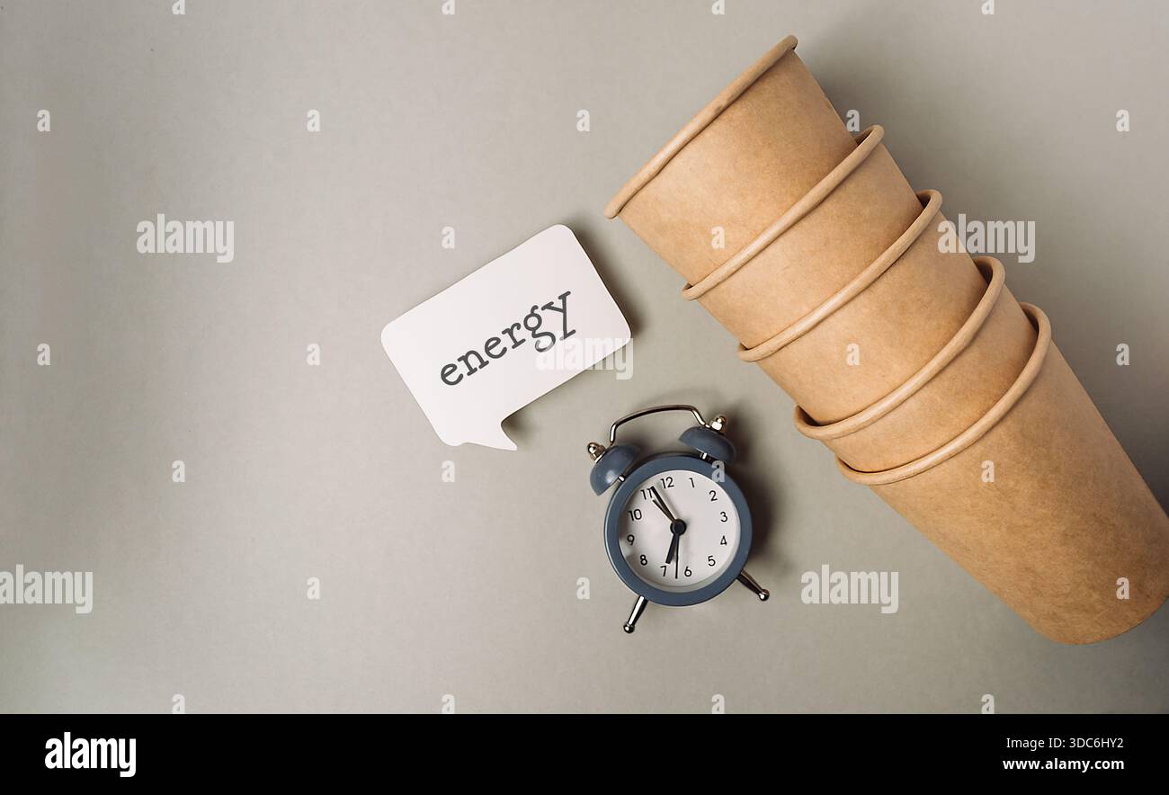 Neben einem Vintage-Wecker und einer Sprechblase werden umweltfreundliche Pappbecher gestapelt, die für Nachhaltigkeit und Umweltfreundlichkeit sorgen Stockfoto