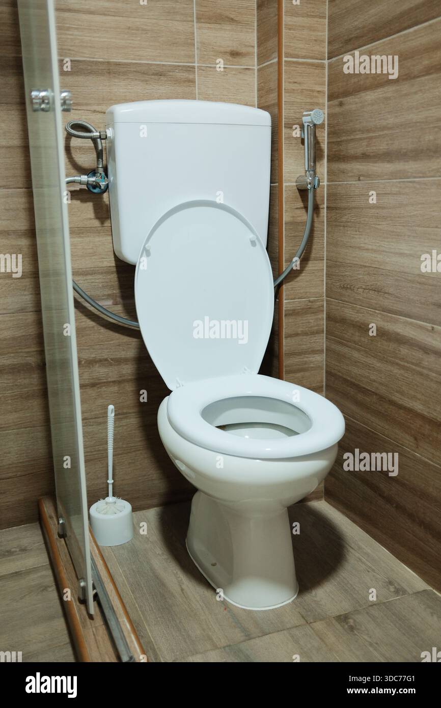 Minimaler Badezimmerbereich mit Toilette und Bidet-Dusche in modernem Apartment. Funktionelle sanitäre Einrichtung, die Sauberkeit, Hygienegewohnheiten und betont Stockfoto