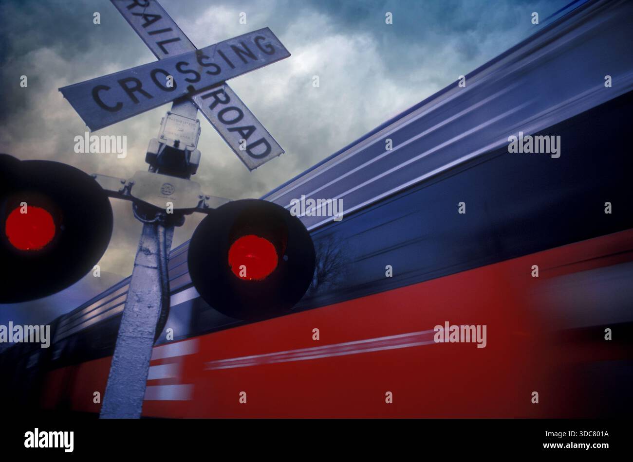 Bahnübergangssignale werden mit roten Lichtern aktiviert, wenn ein Zug den Übergang passiert. Der Himmel ist voller Wolken, die eine dramatische sce erzeugen Stockfoto