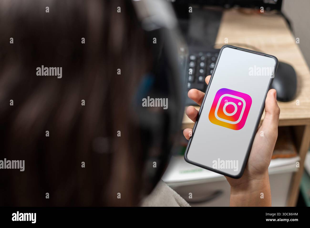 Ein nicht erkennbarer weiblicher Teenager hält ein Handy mit dem Instagram-Logo auf dem Bildschirm Stockfoto