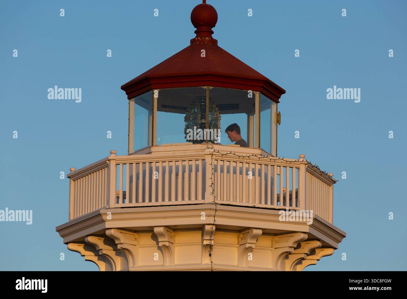 Ein Pfleger führt Wartungsarbeiten an der Fresnel-Linse der Mukilteo Light in Mukilteo, Washington durch. Stockfoto