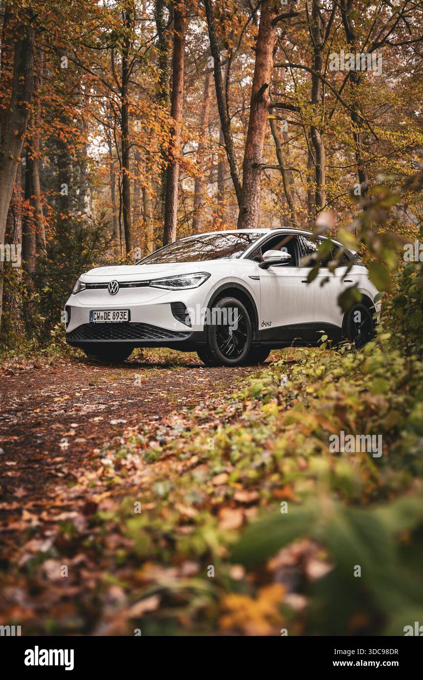 Ein weißer SUV auf einem Waldweg umgeben von Herbstbäumen und Laub, Deer E-Carsharing, VW ID4, Calw, Deutschland Stockfoto