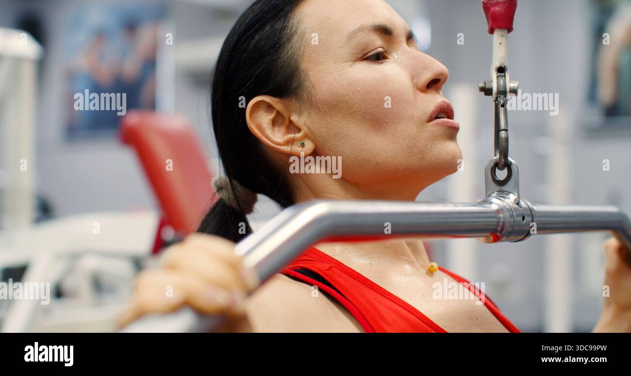 Fitness-Frau, die Pulldown-Training im Fitnessstudio ausübt. Eine Frau, die im Fitnessstudio auf einem Latgerät Sport macht. Die Frau führt lat Pulldowns durch, um zu stärken und Stockfoto