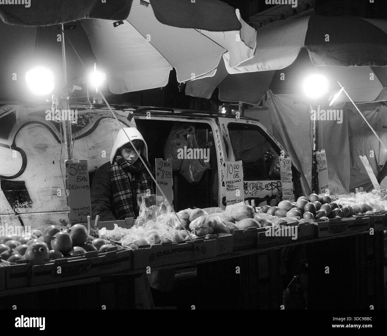Straßenverkäufer verkauft nachts Obst an einem Stand im Freien in New York City, USA. Stockfoto