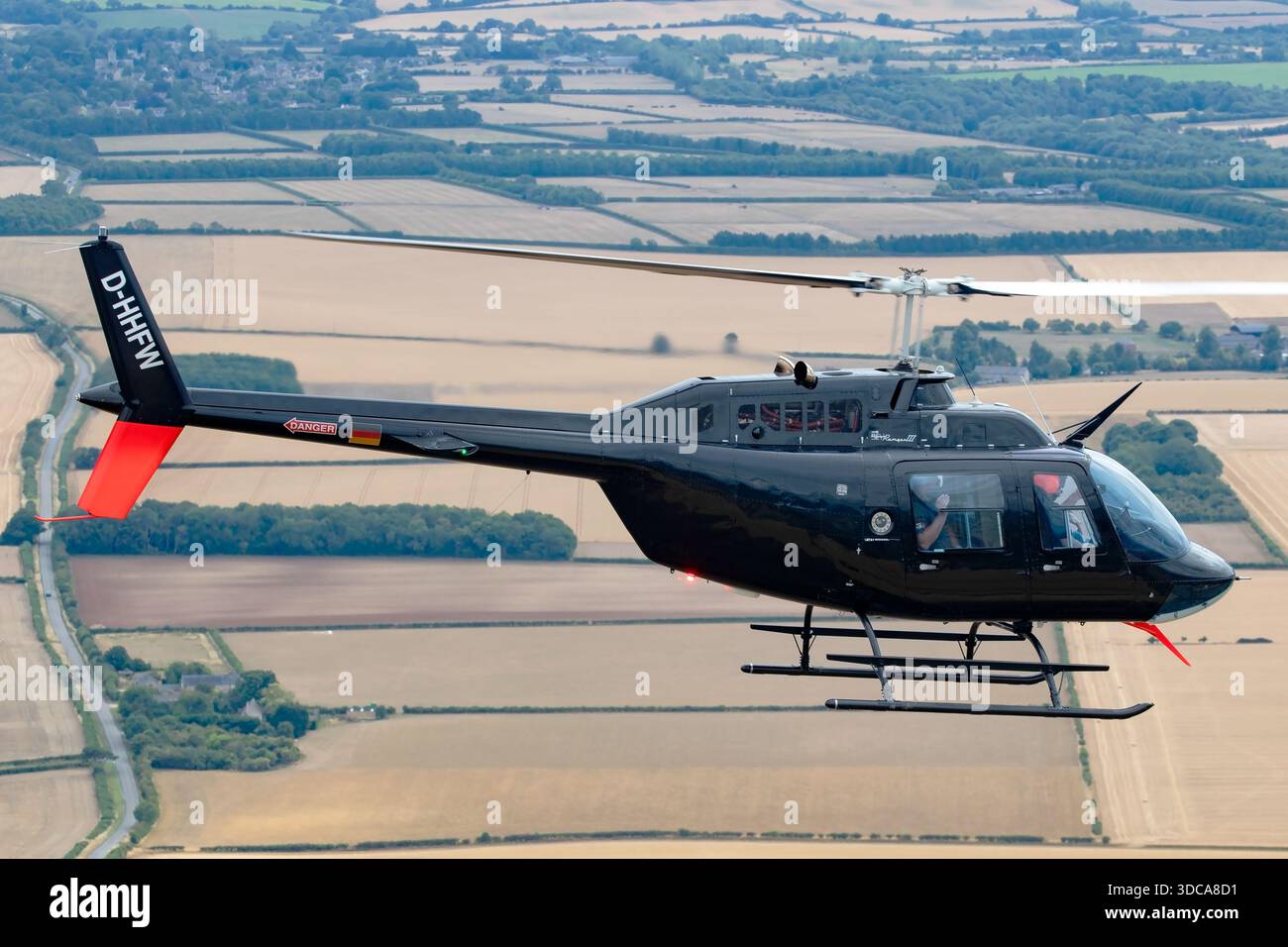 Luft-Luft-Ansicht eines Bell 206B JetRanger III Hubschraubers, der von Heliteam während des Royal International Air Tattoo in Fairford, England, betrieben wurde. Die Luftfahrzeugkennzeichnung D-HHFW ist sichtbar. Das Bild zeigt den leichten Hilfshubschrauber im Flug und hebt die Kabine, die Kufen, das Rotorsystem und die äußeren Markierungen während der Flugschau hervor. Stockfoto
