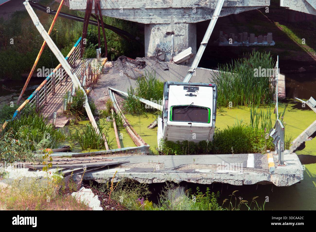 Eine ruinierte Straßenbrücke mit einem weißen Van stürzte im Fluss ab. Das Konzept der Kriegsfolgen, der Zerstörung der Infrastruktur und der humanitären Krise Stockfoto