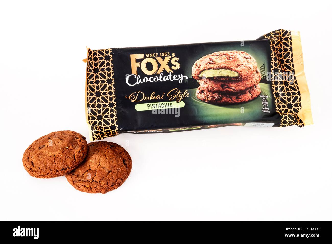 Ein geöffnetes Paket mit Fox's Chocolatey Dubai Style Pistazienkeksen mit zwei Keksen neben dem Paket. Stockfoto