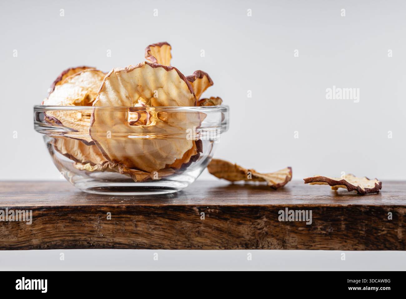 Apfelchips in einer Glasschale auf hellgrauem Hintergrund. Ein gesunder und köstlicher Snack voller Vitamine. Geeignet für Vegetarier. Stockfoto