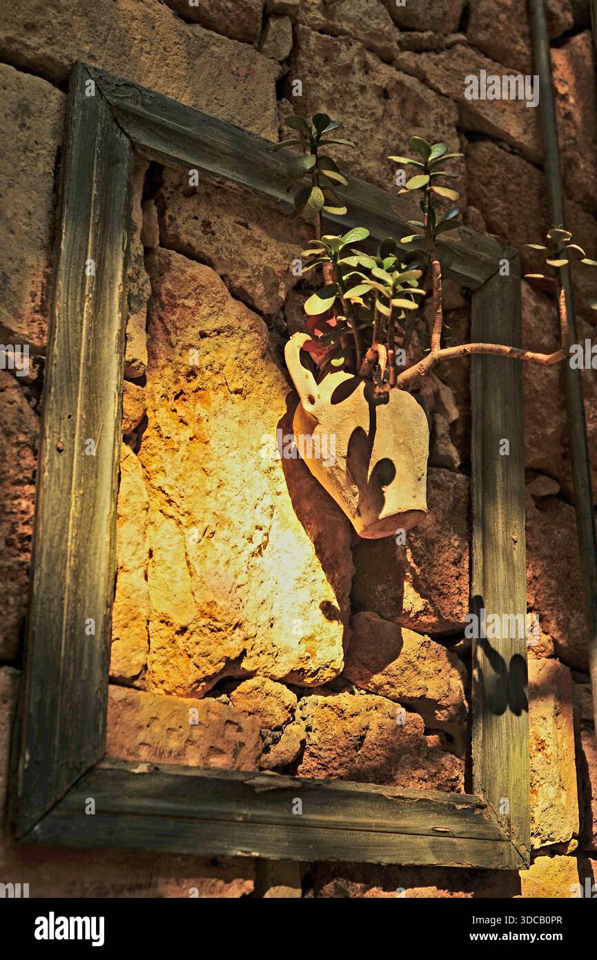 Rustikale Vase an der Wand mit Picknickrahmen in einem Restaurant ohne Dach. Erschossen in Rethymno, Kreta. Stockfoto