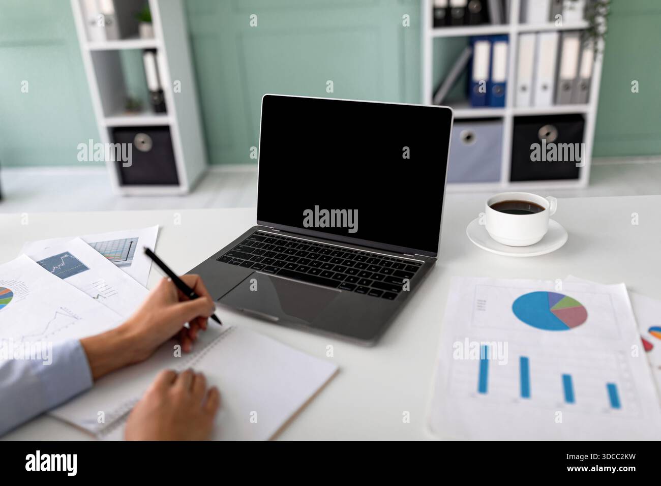 Eine Geschäftsführerin oder Finanzmanagerin nimmt an einer Online-Konferenz Teil. Sie macht sich Notizen zu wichtigen Informationen, während sie ihren Laptop mit einem leeren SC verwendet Stockfoto