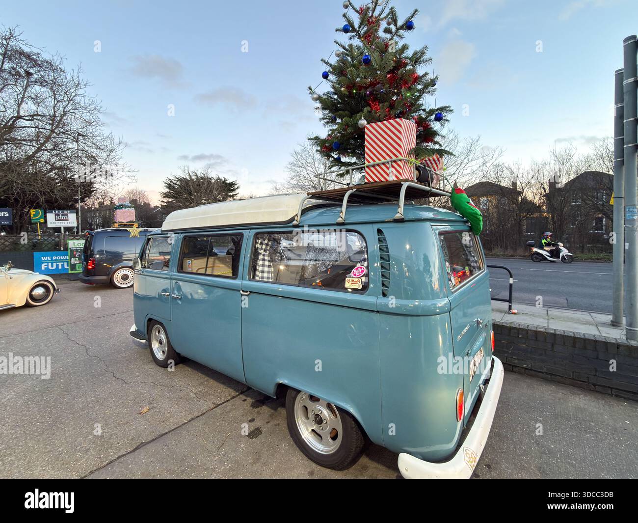 Klassischer hellblauer Volkswagen T2 Wohnmobil mit Weihnachtsbaum und Geschenken auf einem Dachträger bei einem festlichen Fahrzeugtreffen in London, Großbritannien. Stockfoto