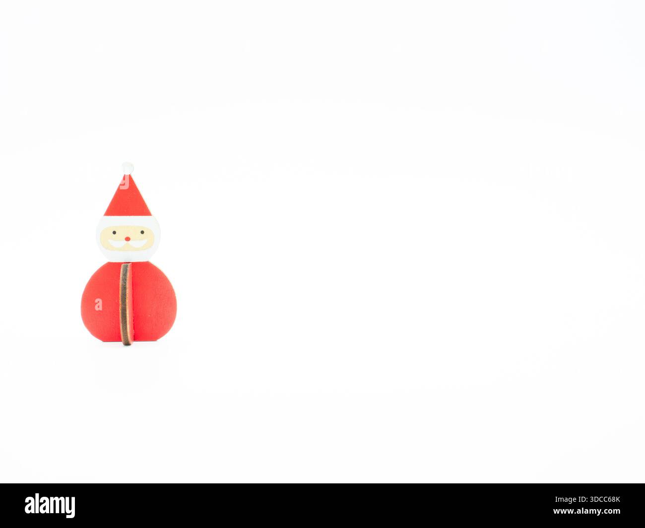Eine hölzerne Weihnachtsmannsdekoration steht links. Fotografiert auf Augenhöhe vor weißem Hintergrund. Stockfoto