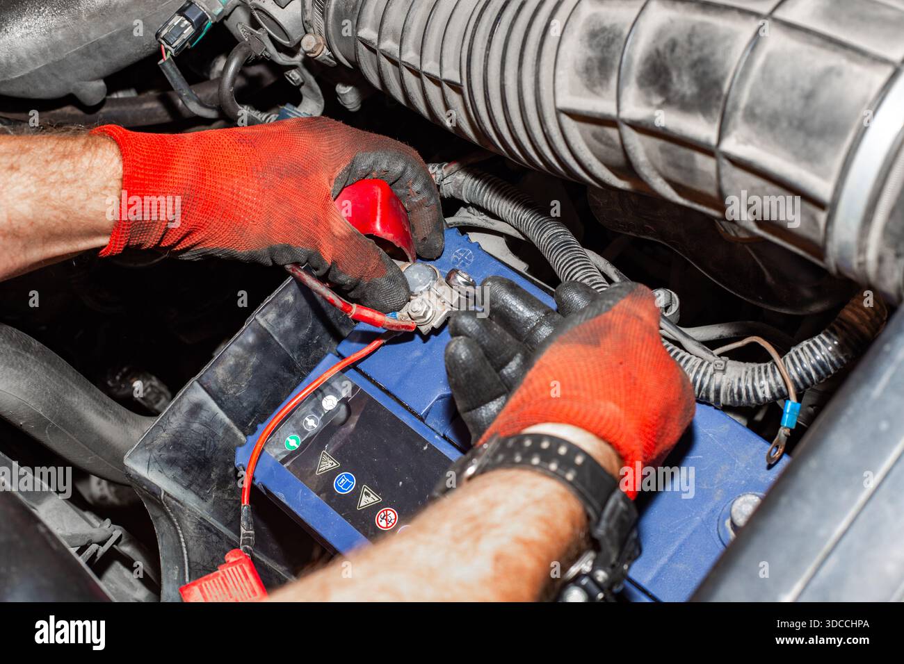 Hände mit Handschuhen Verwenden Sie einen Schraubenschlüssel, um die Batterieanschlüsse während der Wartung und Reparatur des Fahrzeugs zu lösen. Stockfoto