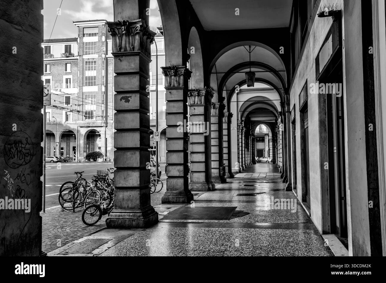 Schwarz-weiß-Blick auf die historischen Säulenvorsprünge von Bologna mit sich wiederholenden Bögen und Säulen. Stockfoto