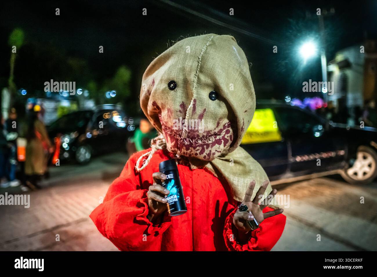Santa Maria del Tule, Mexiko - 03. November 2023: Blick auf eine Person, die am Tag des Todes verkleidet wurde, mit einer Sackmaske und einem roten Gewand, embo Stockfoto