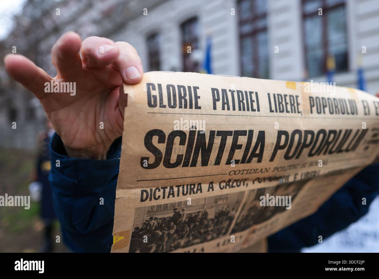 Bukarest, Rumänien - 21. Dezember 2025: Details mit den Händen eines alten Mannes, der eine Scinteia-Zeitung aus der kommunistischen Ära hält. Stockfoto