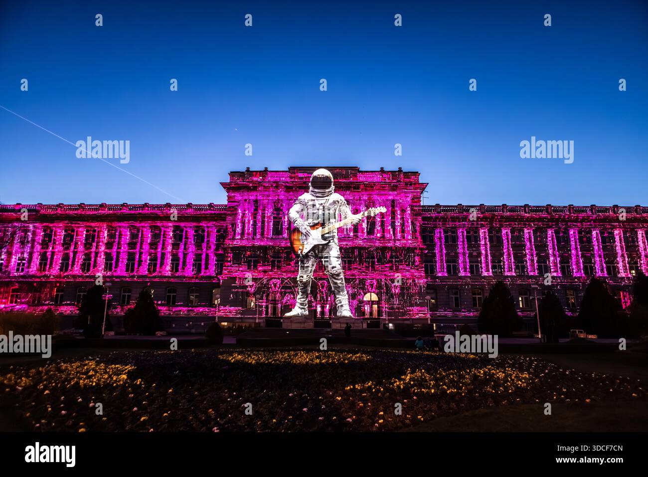 Zagreb, Kroatien - 16. März 2023: Blick auf den Art Pavillon in leuchtendem rosafarbenem Licht, ein Astronaut mit einer Gitarre, die auf seine Fassade projiziert wird, erzeugt Stockfoto