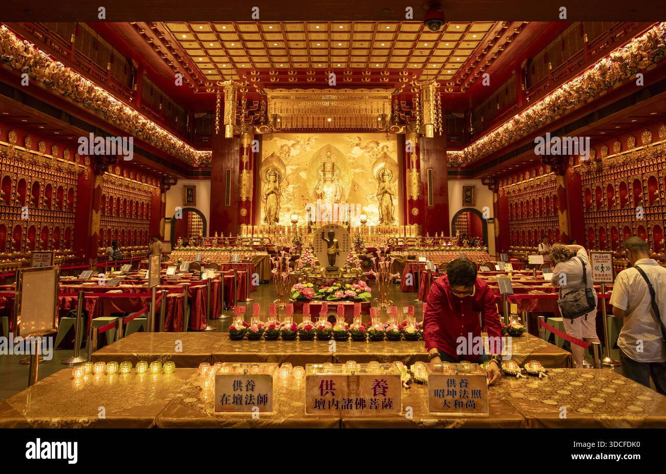Singapur, Singapur - 14. Mai 2024: Blick auf den reich geschmückten Buddha-Zahn-Reliquientempel, getaucht in warmes goldenes Licht, wo sich die Gläubigen inmitten des Tempels versammeln Stockfoto
