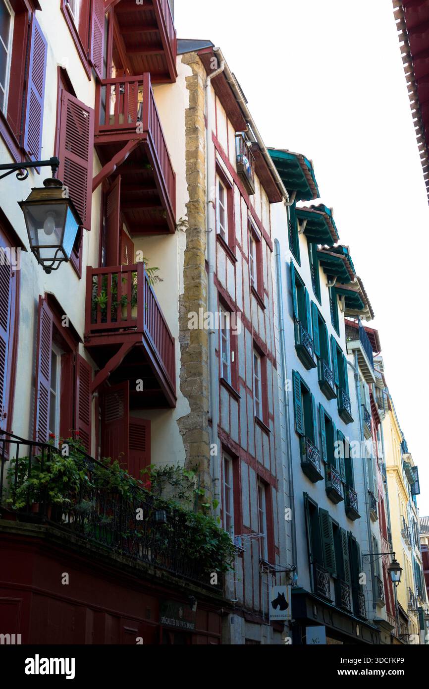 Der Blick auf alte Gebäude erhebt sich mit bunten Fensterläden und Holzrahmen, die sich vom hellen Himmel abheben und das Wesen des urbanen Charmes, Bayon, einfangen Stockfoto