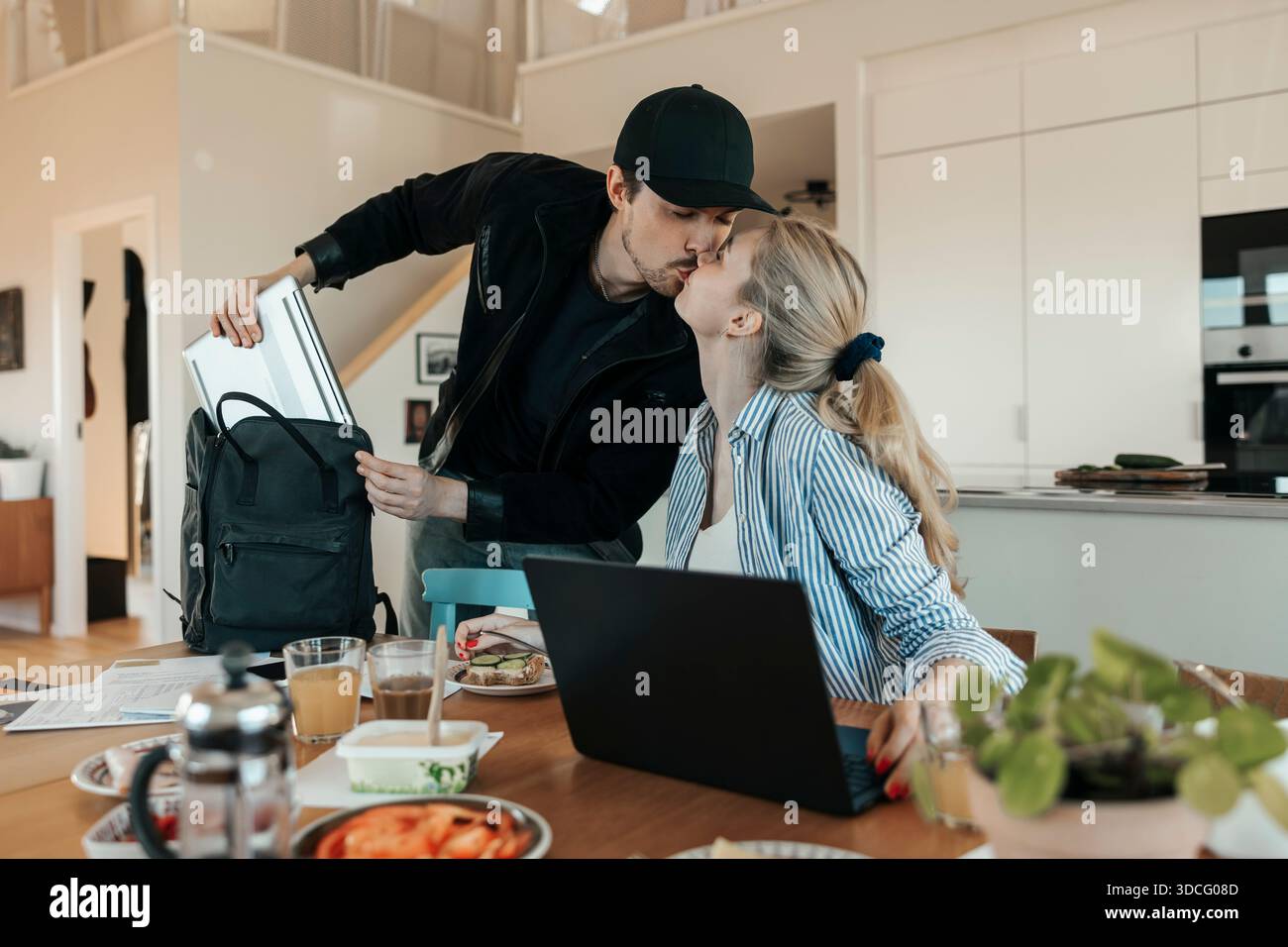 Junger Mann, der seine Freundin küsst, bevor er zur Arbeit geht Stockfoto