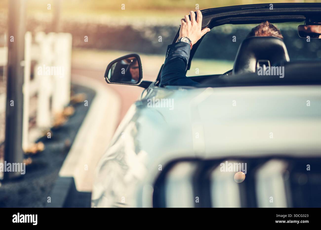 Eine Person fährt mit einem Cabrio eine kurvenreiche Straße hinunter und genießt das warme Wetter und die offene Luft auf dem Land. Stockfoto
