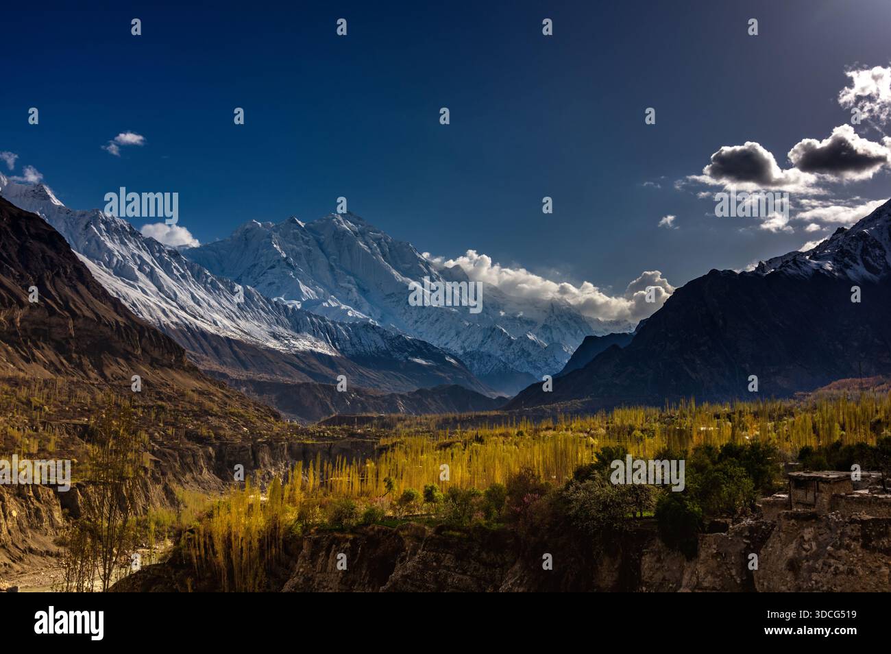 Blick auf schneebedeckte Berge durchdringen den azurblauen Himmel und werfen lange Schatten über den goldenen Talboden, ein starker Kontrast in Hunza, Gilgit Baltistan, Stockfoto