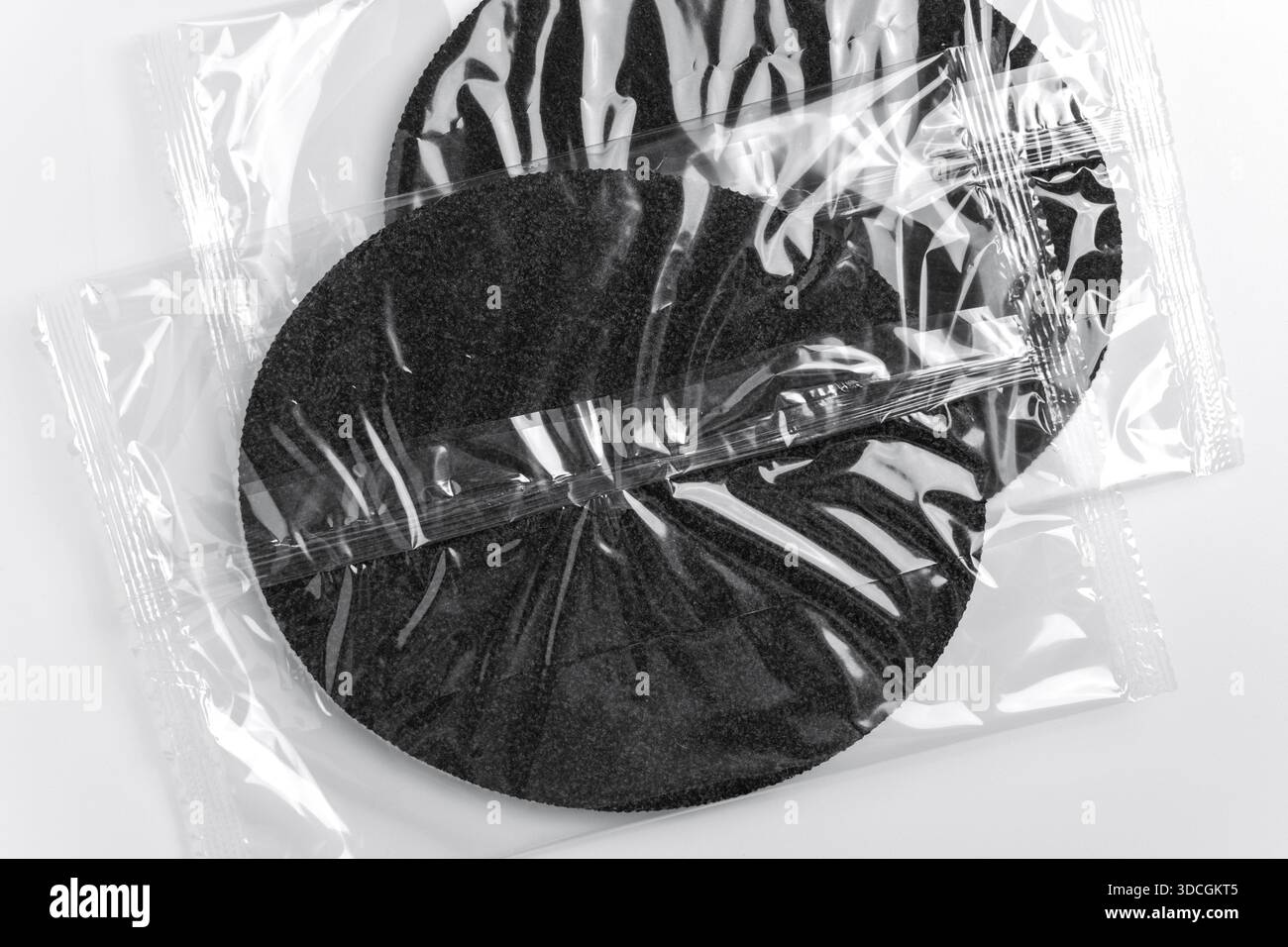 Kreisförmiges Filterelement in transparenter Packung auf hellem Hintergrund. Technische Filterkomponente. Konzept der Instandhaltungsressourcen Stockfoto