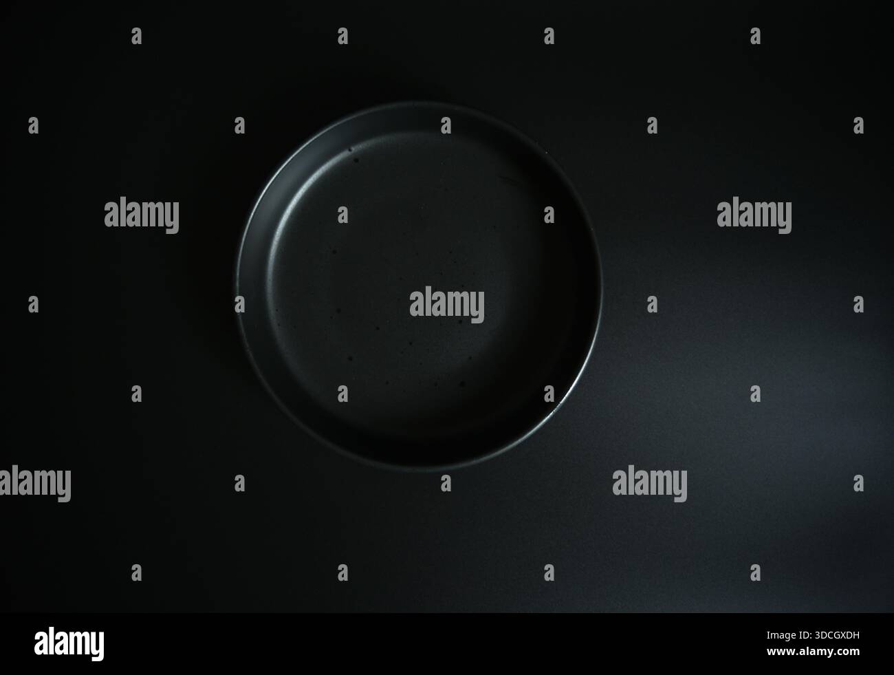 Sauberes minimalistisches schwarzes Geschirrmodell. Draufsicht auf dunklem Hintergrund. Perfekt für das Design von Speisen, die Präsentation von Menüs und das Branding im Restaurant. Stockfoto