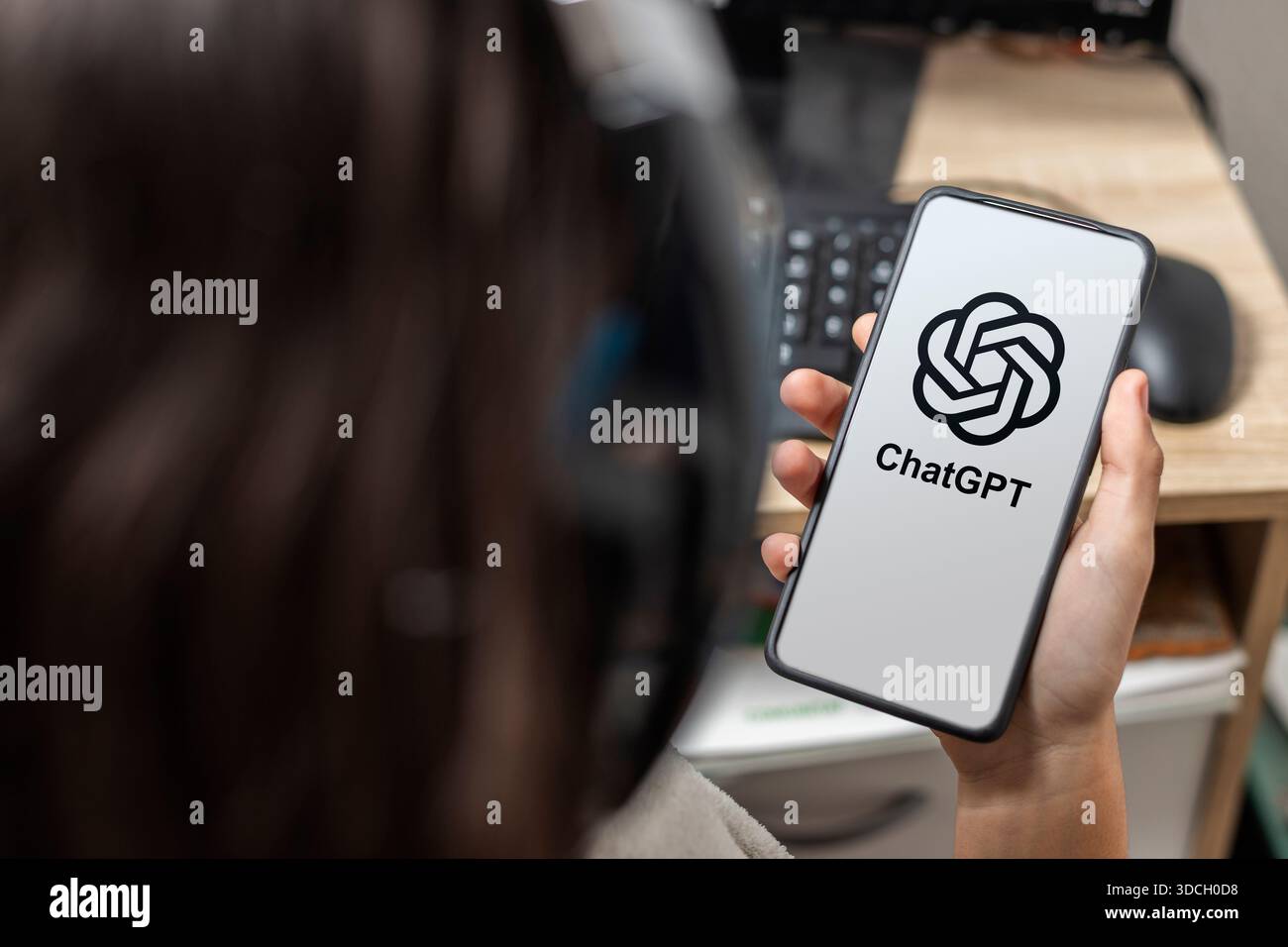 Ein nicht erkennbarer weiblicher Teenager hält ein Mobiltelefon mit ChatGPT-Logo auf dem Bildschirm mit weißem Hintergrund Stockfoto