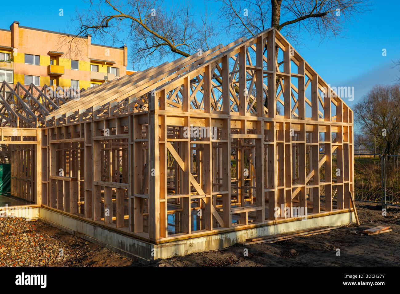 Holzhausrahmen im Bau mit Dachbalken auf städtischer Baustelle Stockfoto