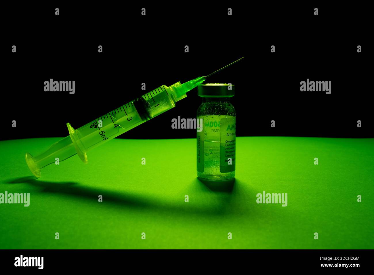 Spritze und Fläschchen mit grüner Beleuchtung für einen dramatischen Effekt. Stockfoto