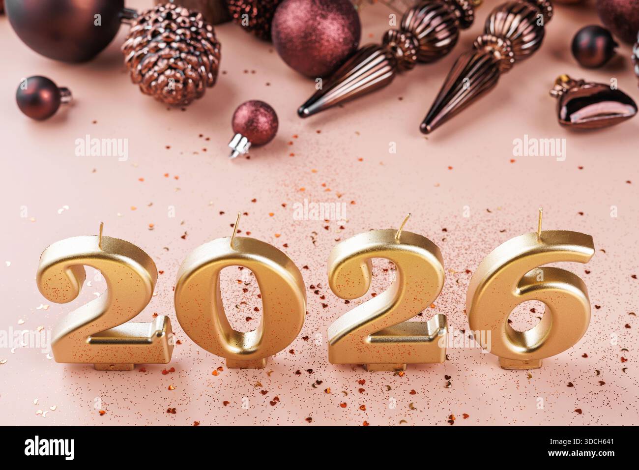 Goldene 2026 Kerzen mit Weihnachtskugeln auf Rosa Stockfoto